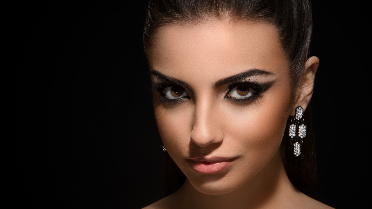 Красивая кареглазая девушка с прической на черном фоне