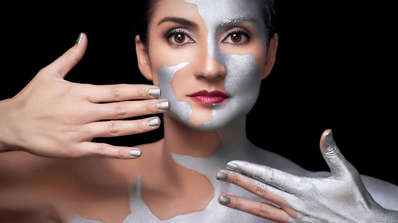 Красивая кареглазая женщина с серебристой краской на теле 