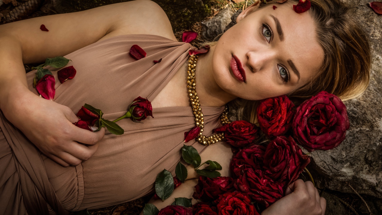 Красивая девушка в платье лежит на земле с розами