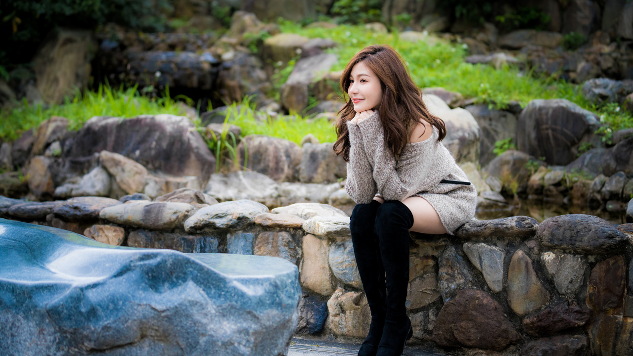 Красивая девушка в кофте сидит у пруда