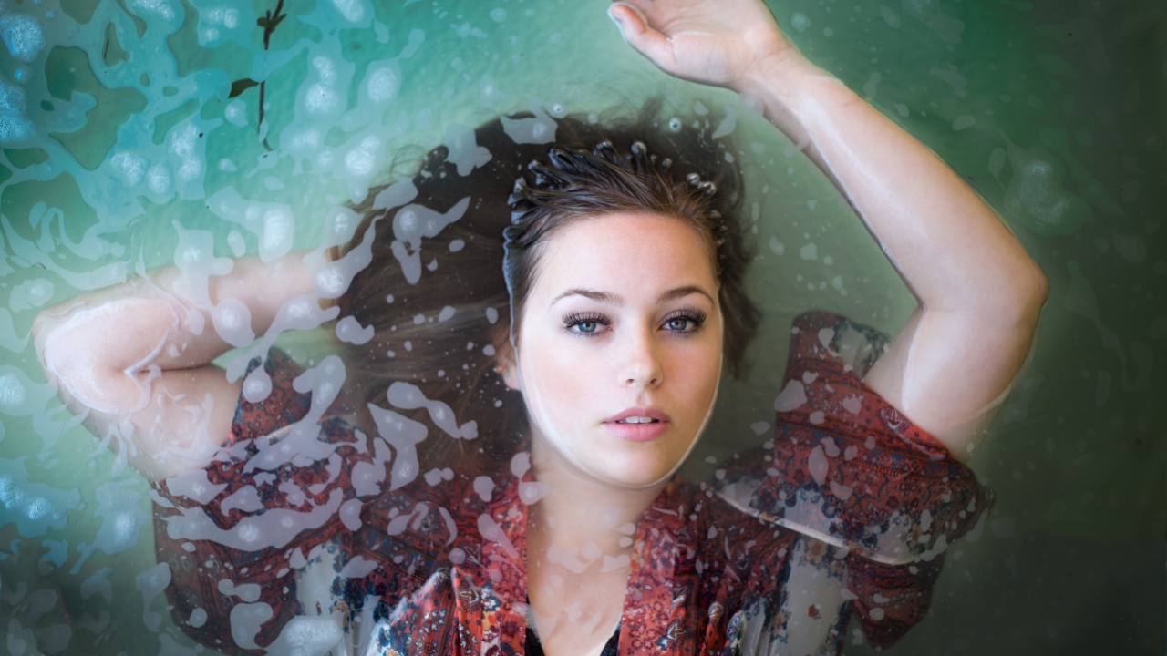 Красивая девушка лежит в одежде в воде 