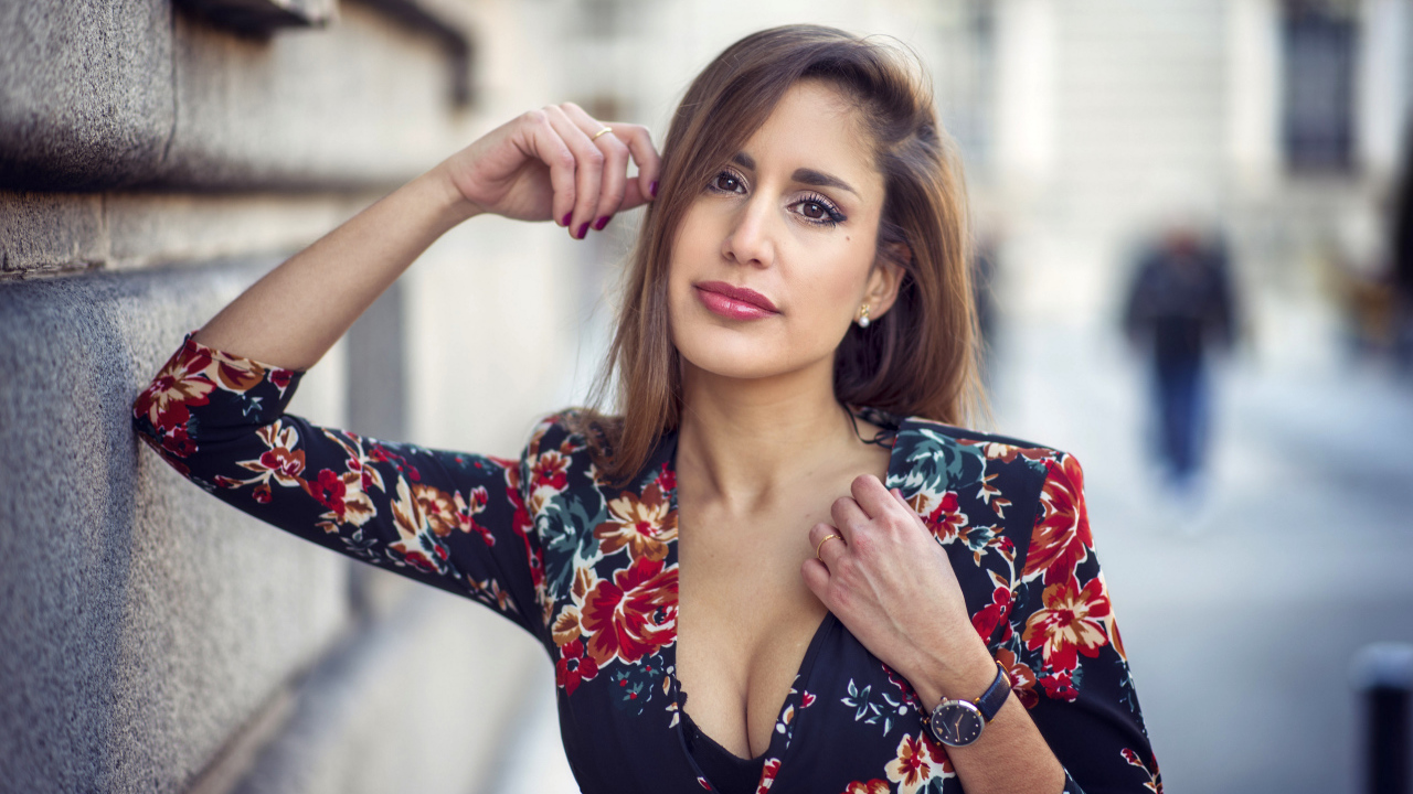 Красивая девушка с часами на руке стоит у стены