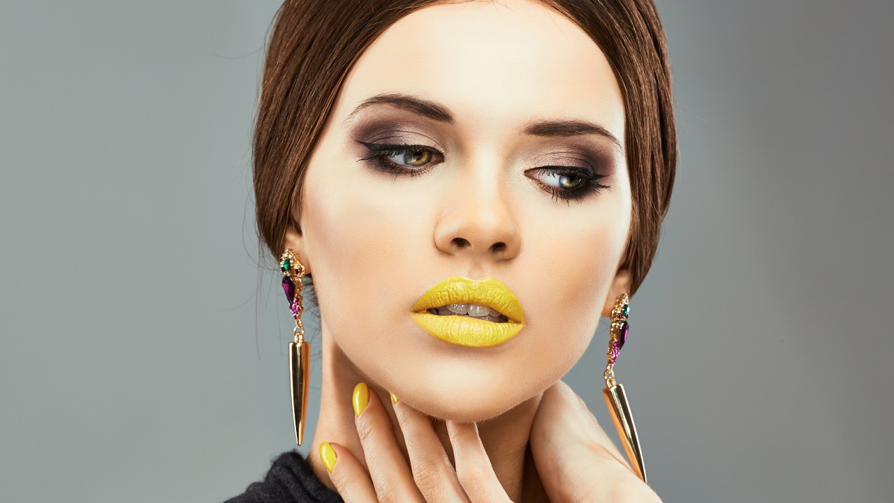 Красивая девушка с дорогими серьгами в ушах на сером фоне