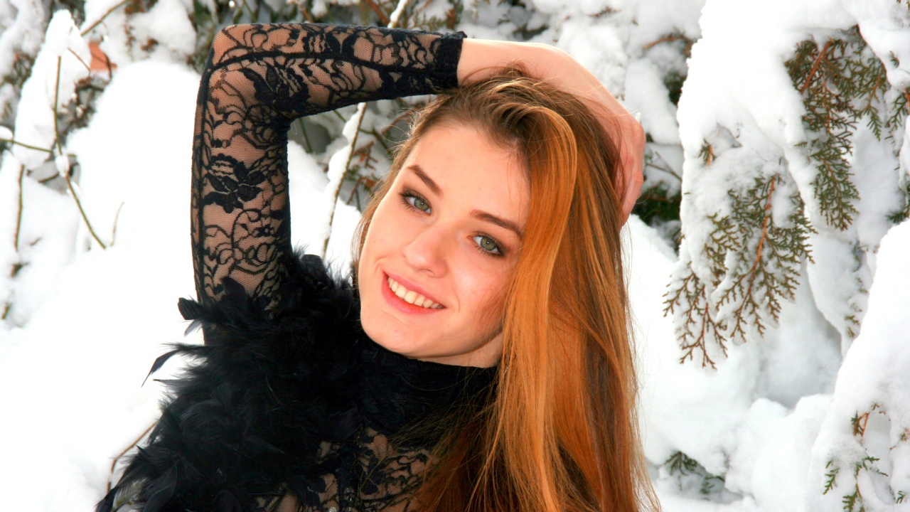 Красивая рыжеволосая девушка у заснеженной туи