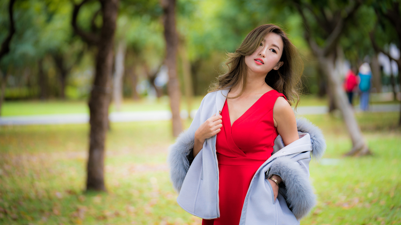 Яркая девушка азиатка в красном платье в парке