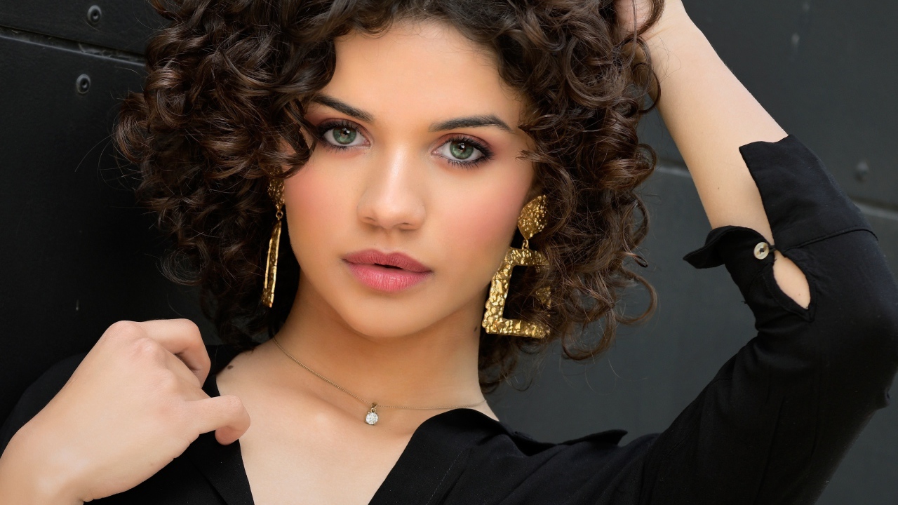 Кудрявая девушка с рукой в волосах в черной рубашке 