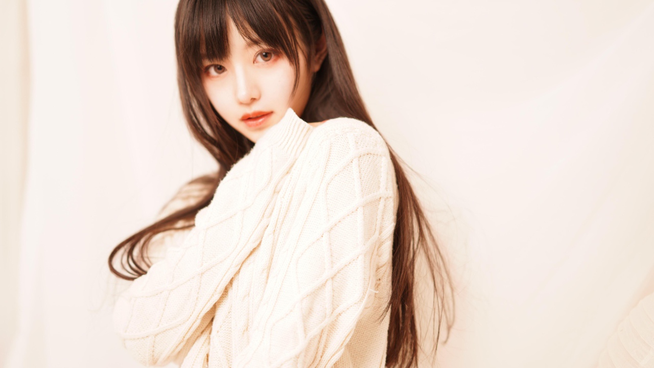 Милая азиатка в белом свитере на розовом фоне