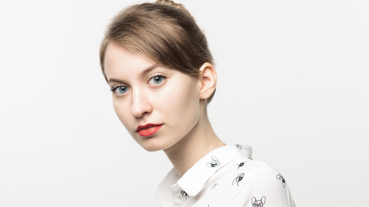 Милая голубоглазая девушка в рубашке на сером фоне