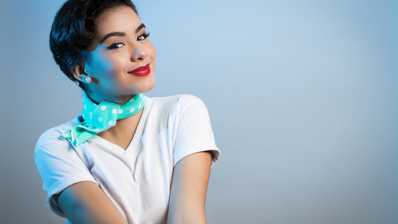 Милая улыбающаяся девушка с шарфом на шее на сером фоне