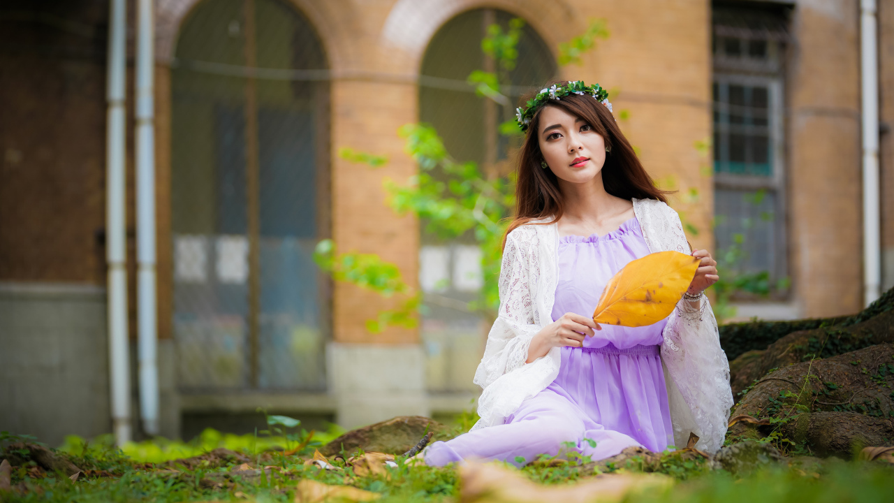 Девушка в красивом платье сидит на траве 