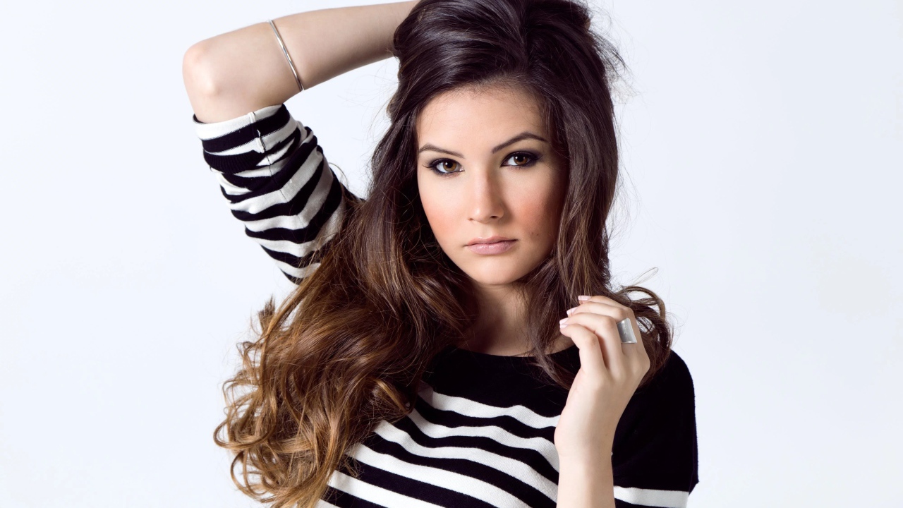 Девушка в полосатом свитере с рукой в волосах на белом фоне