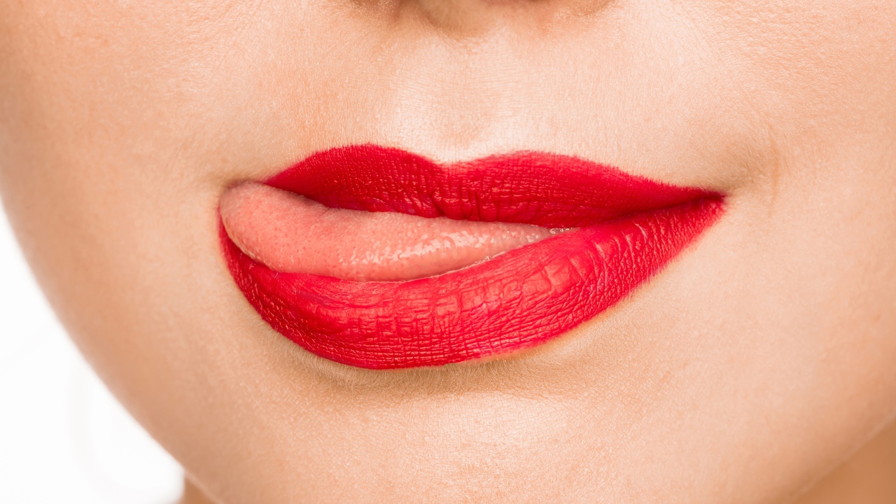 Девушка с  красными губами показывает язык