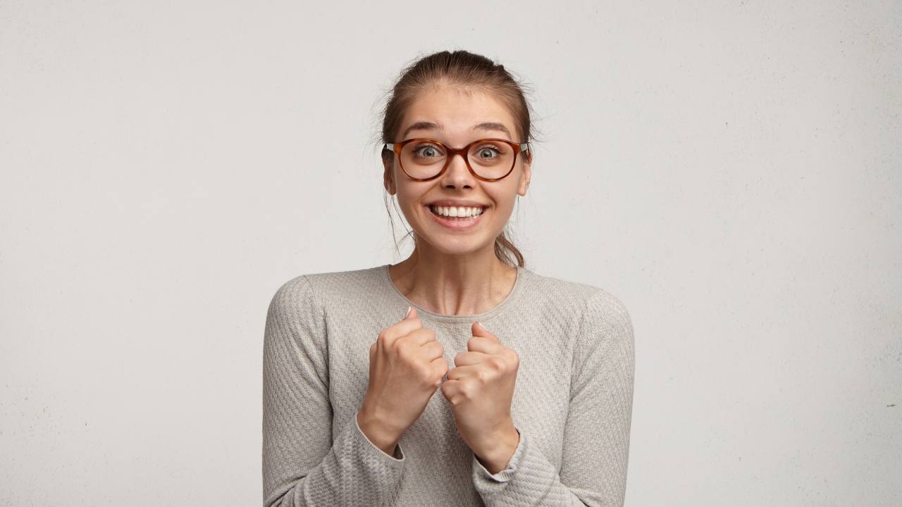 Радостная девушка в очках для зрения на сером фоне 