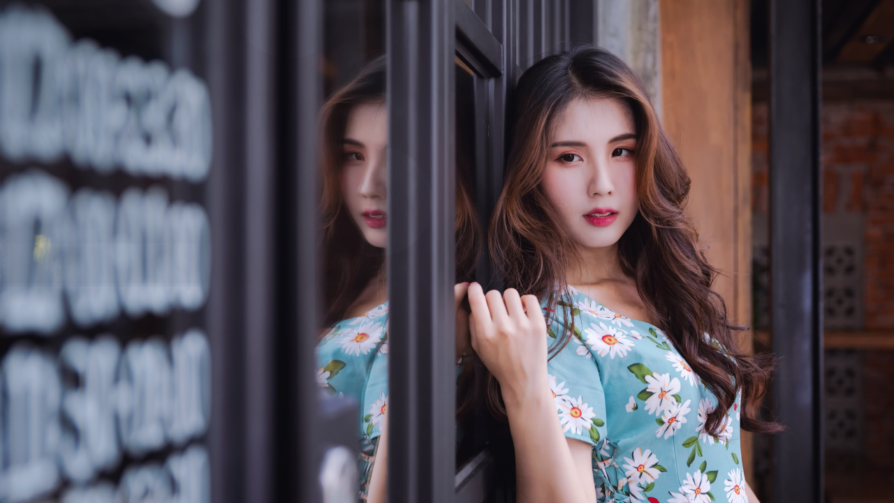 Длинноволосая девушка азиатка стоит у окна