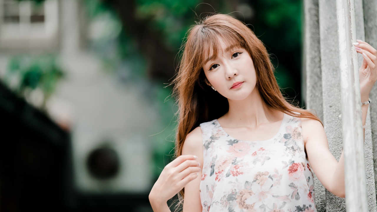 Длинноволосая азиатка стоит у стены 
