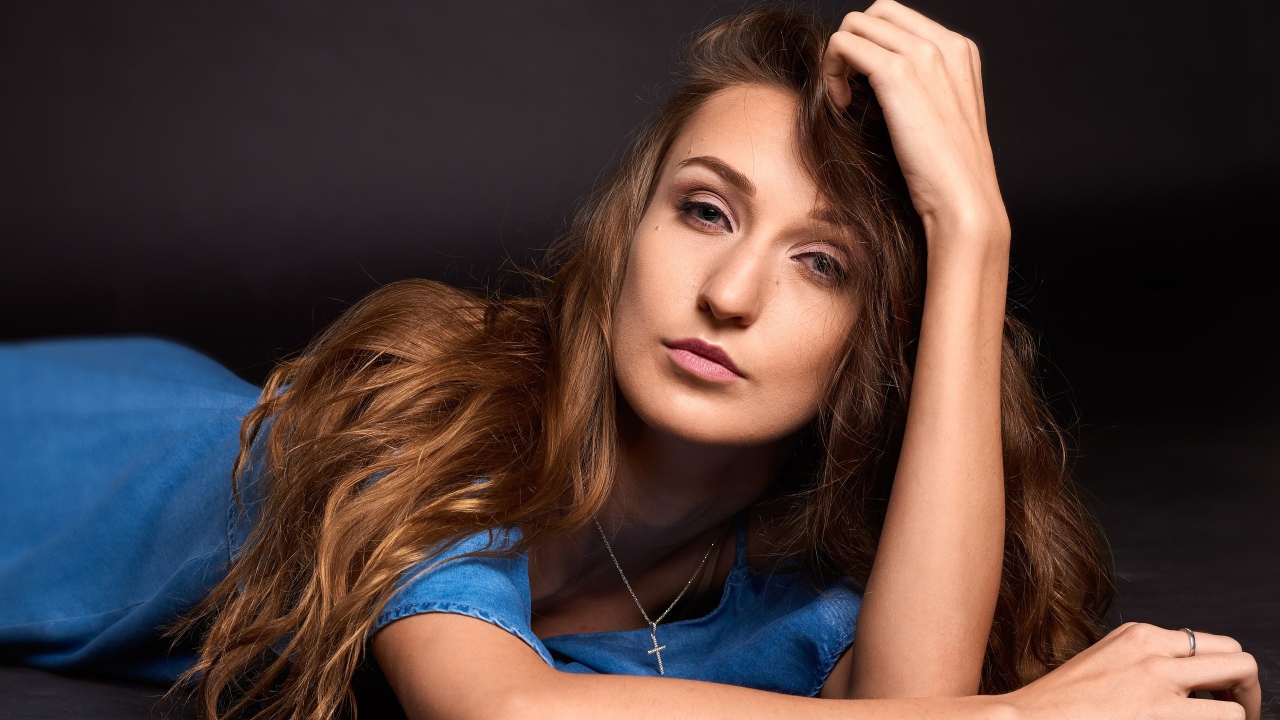 Длинноволосая шатенка лежит на полу в голубом платье 