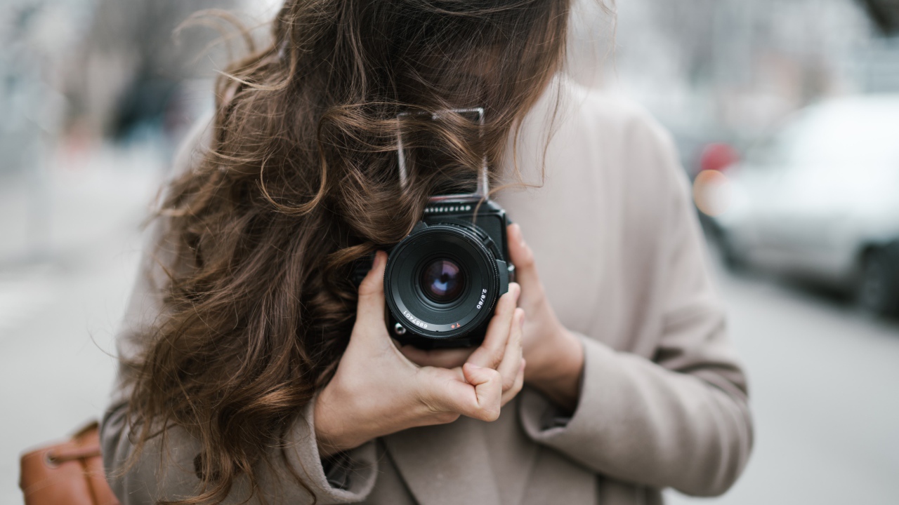 Длинноволосая девушка с фотоаппаратом в руках 