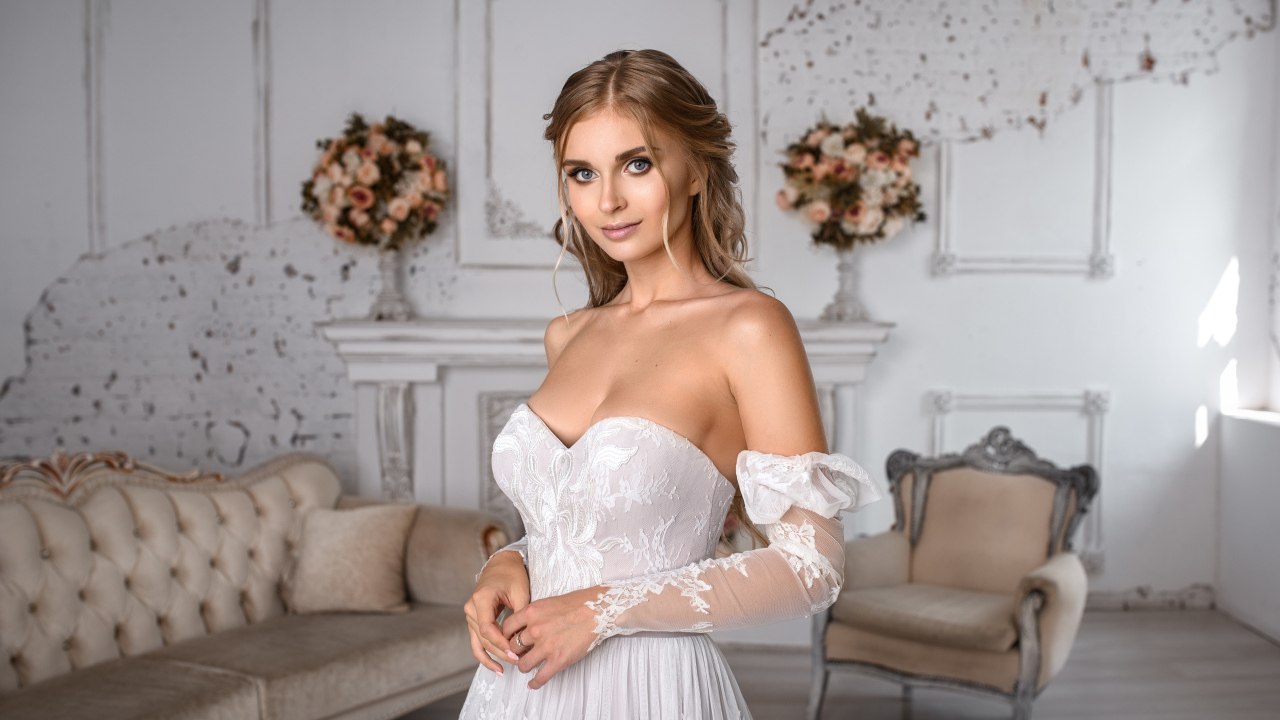 Милая девушка в свадебном платье в комнате с диваном