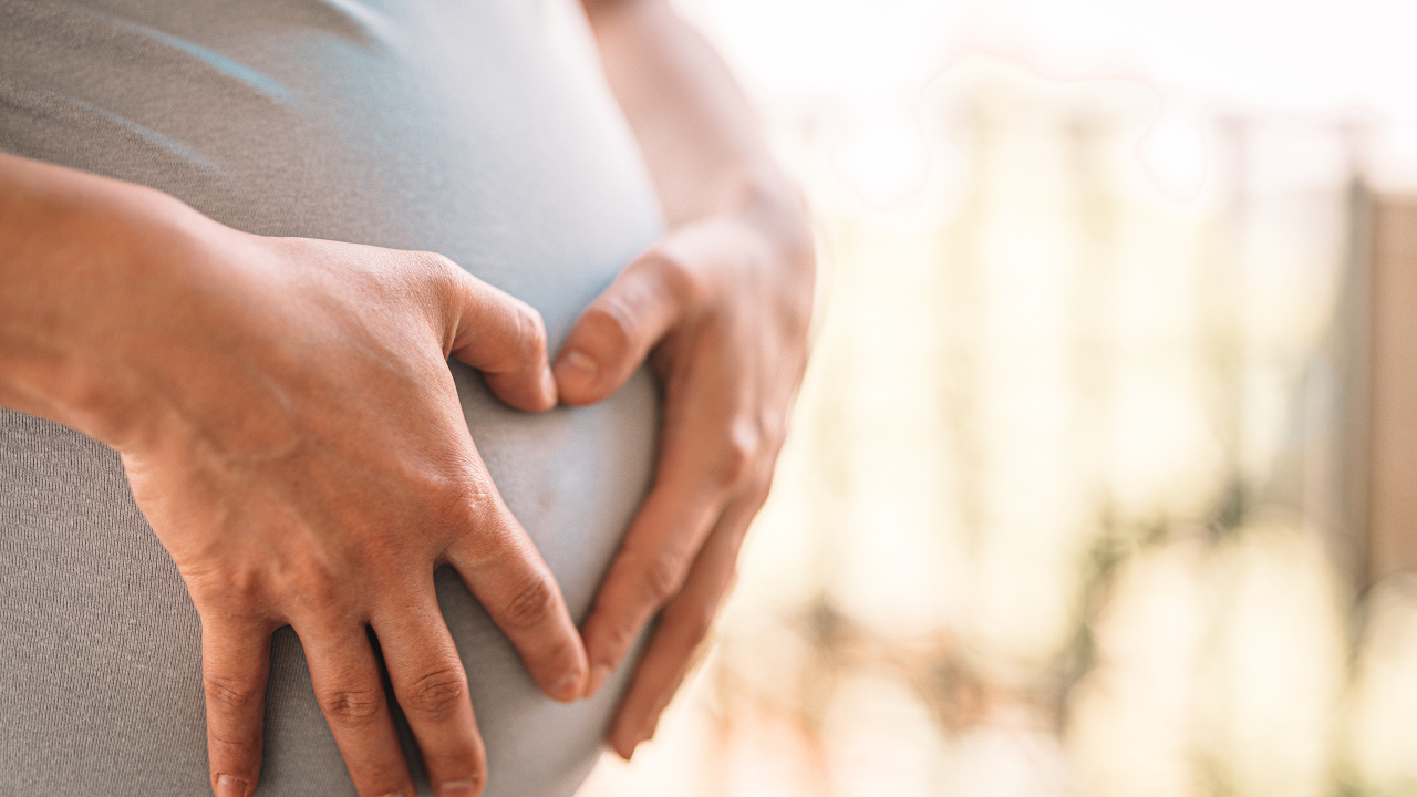 Беременная женщина держит руки на животе 