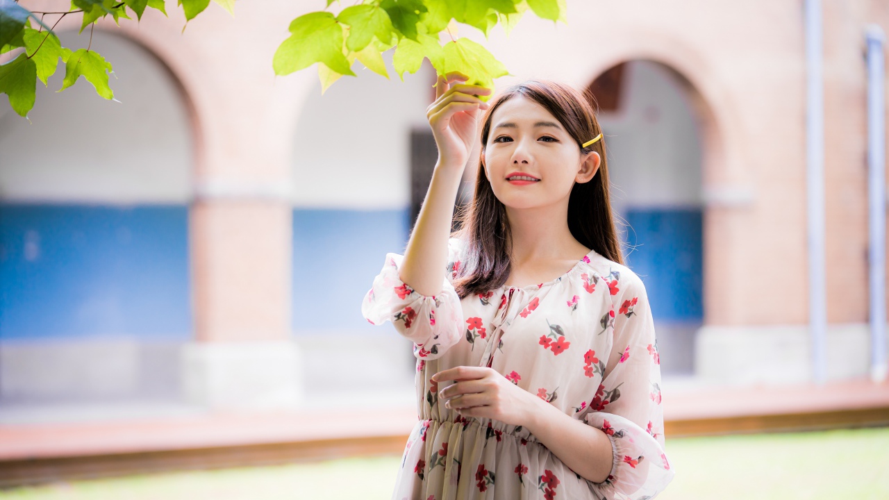 Улыбающаяся девушка в платье у дерева 