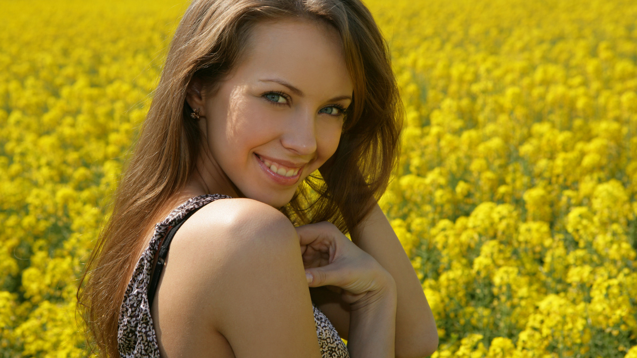 Улыбающаяся девушка на фоне поля с желтыми цветами