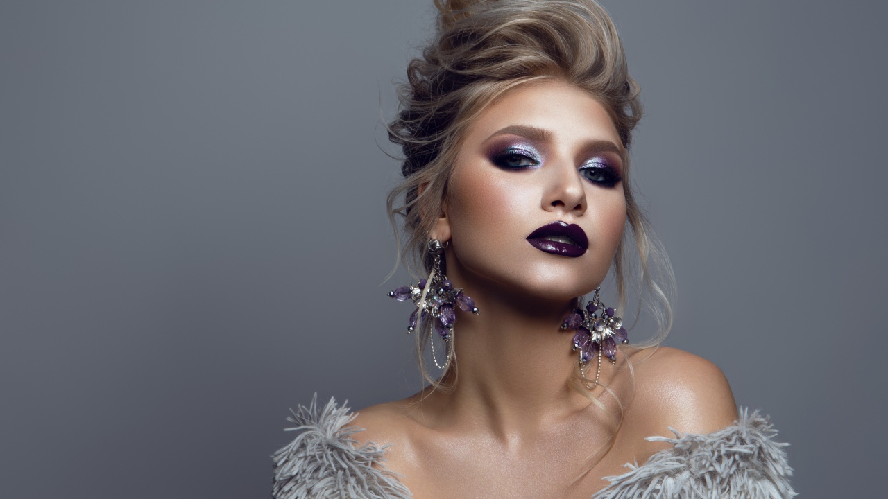 Эффектная девушка с ярким макияжем на сером фоне