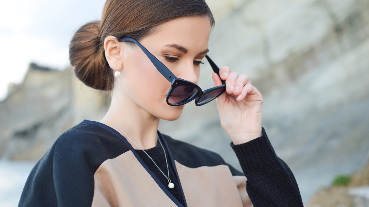 Стильная девушка с прической снимает очки