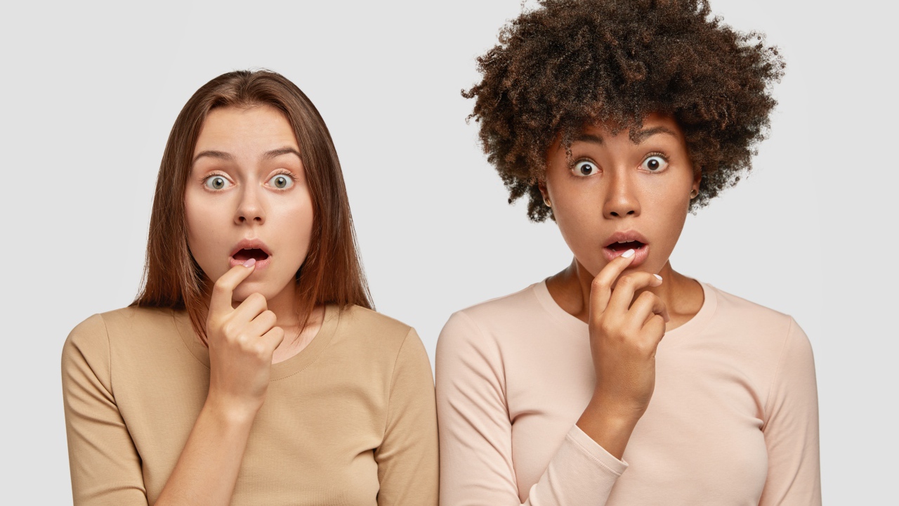 Две удивленные девушки на сером фоне 