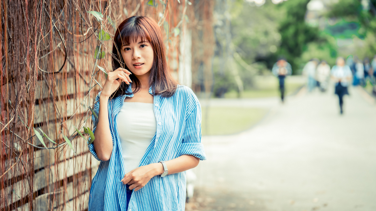 Молодая азиатка в рубашке у стены