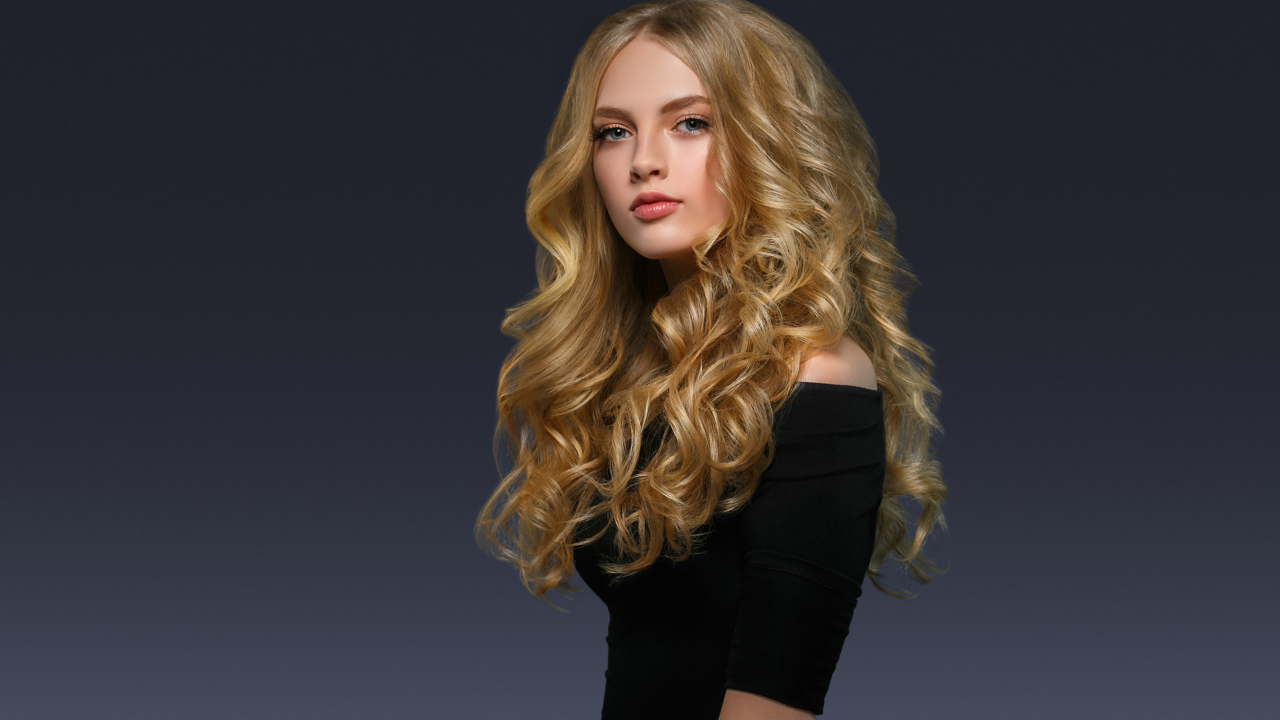 Молодая блондинка с красивыми длинными волосами в черном платье