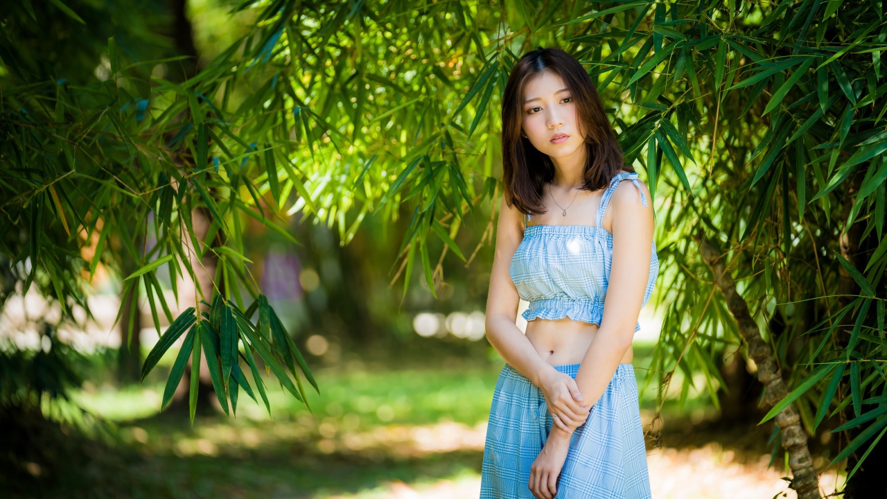 Молодая девушка в голубом костюме под деревом