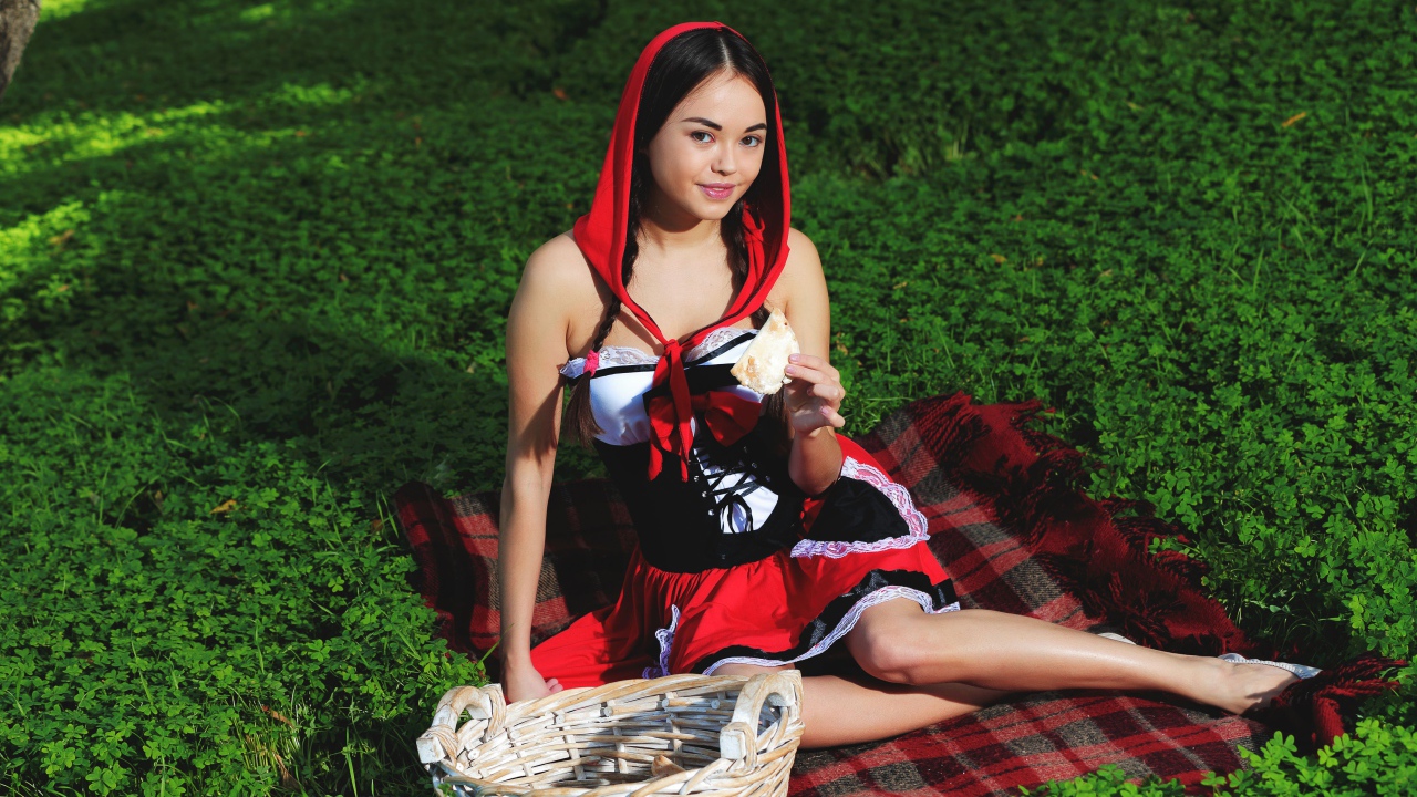 Молодая девушка в костюме сидит на траве, косплей