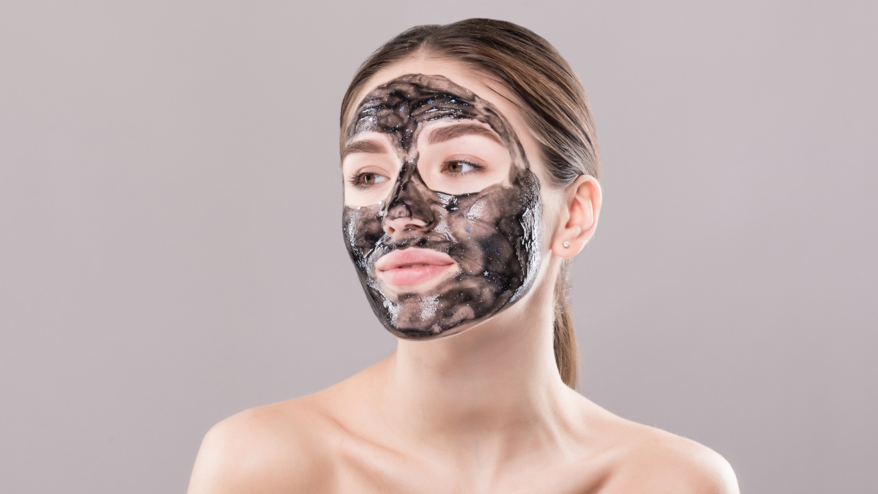 Молодая девушка с косметической черной маской на лице