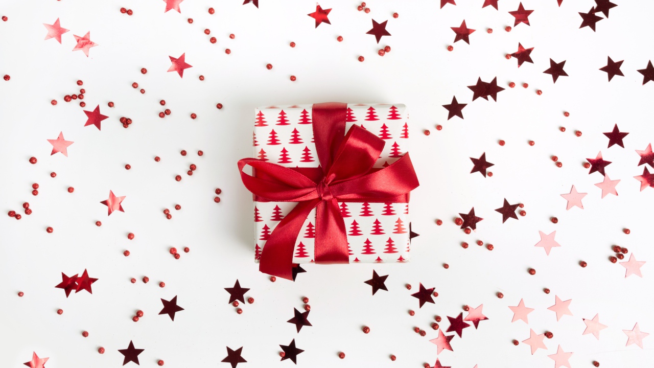 Подарок с красным бантом на белом фоне со звездочками