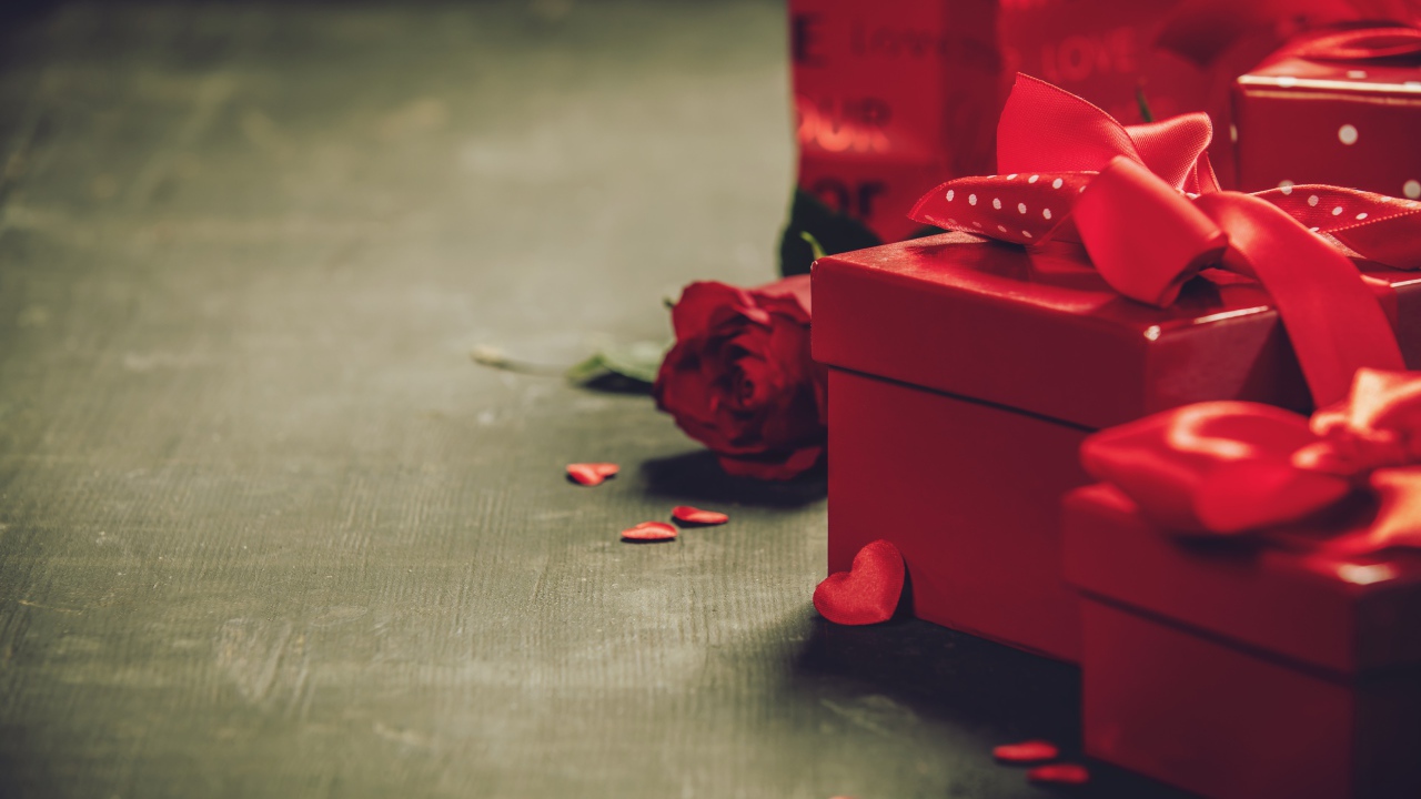 Красные коробки с подарками на столе с розой 