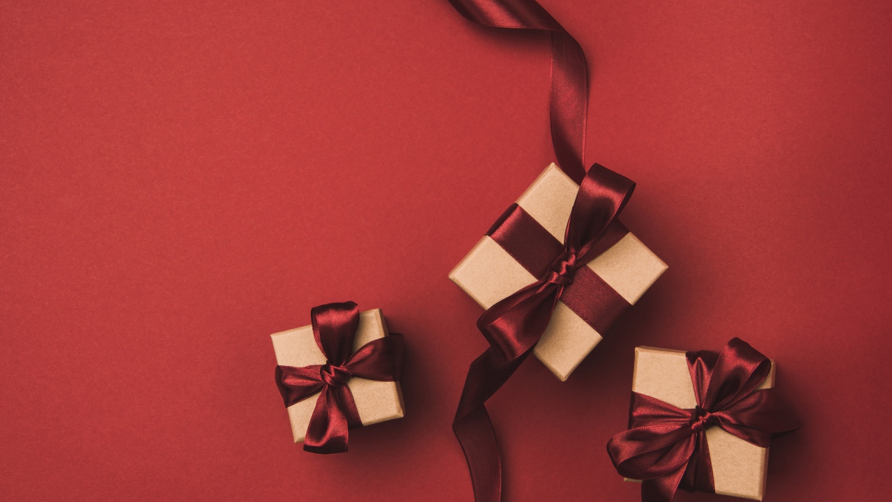Три подарочные коробки с бантами на красном фоне