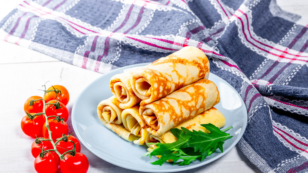 Pancakes on the table with tomatoes and a towel treat for Shrovetide 2020