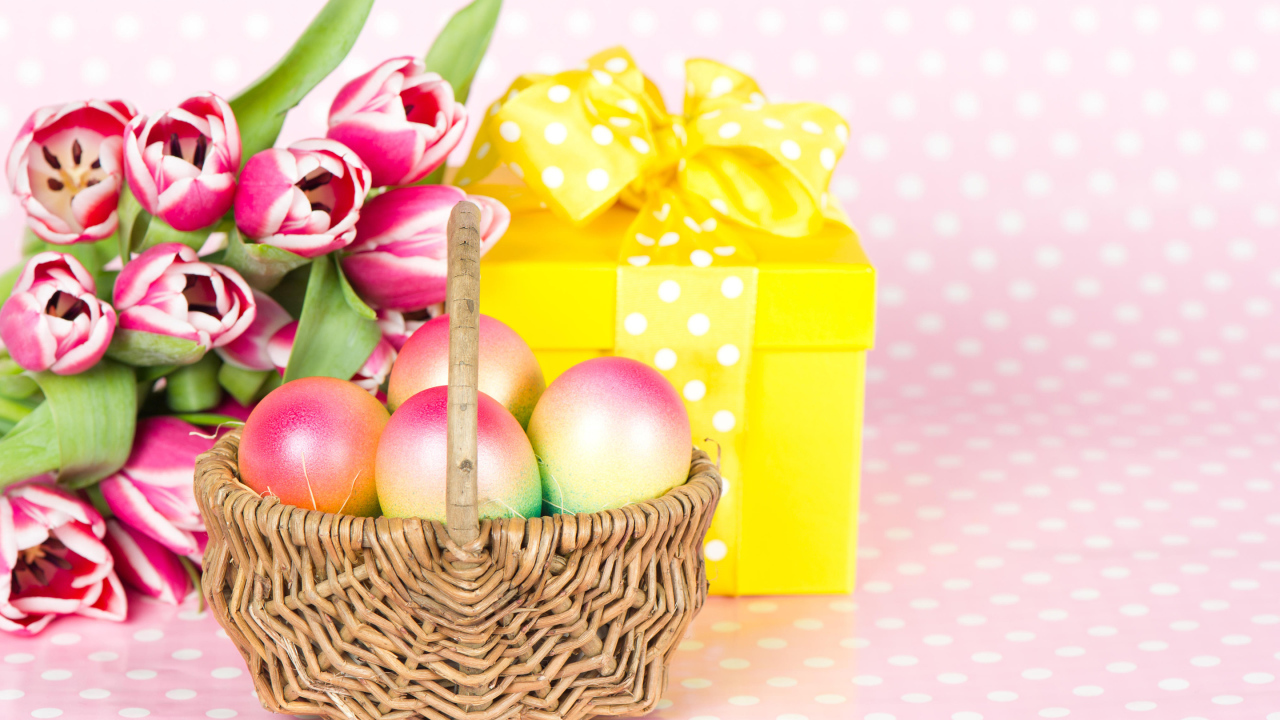 Корзина с пасхальными яйцами на столе с подарком и букетом тюльпанов 