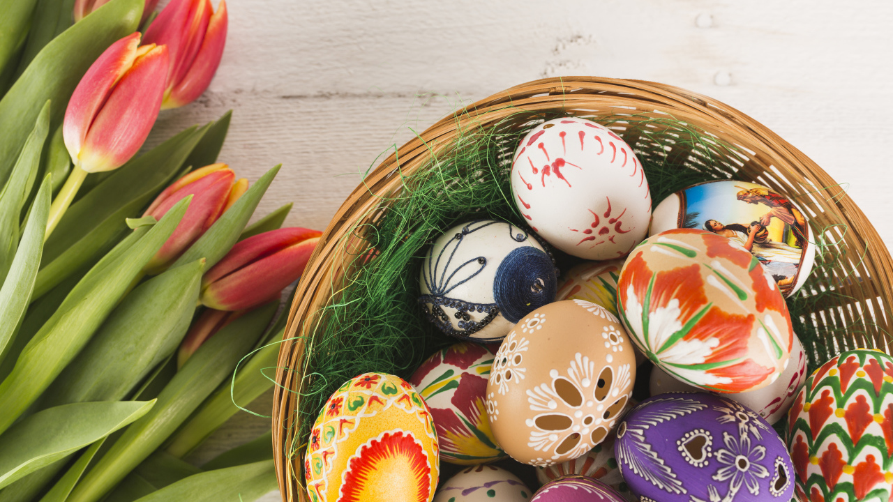 Разноцветные крашеные яйца в корзине с букетом тюльпанов на Пасху