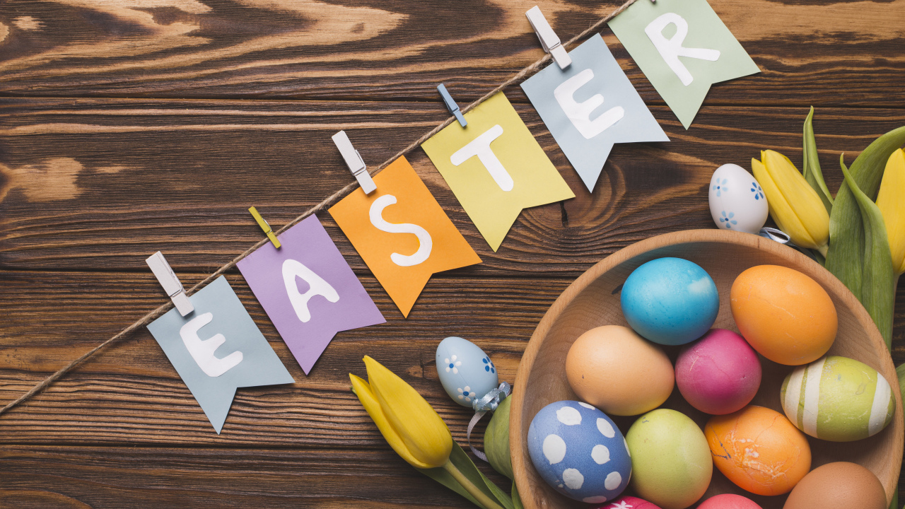 Надпись Пасха на столе с крашеными яйцами и тюльпанами