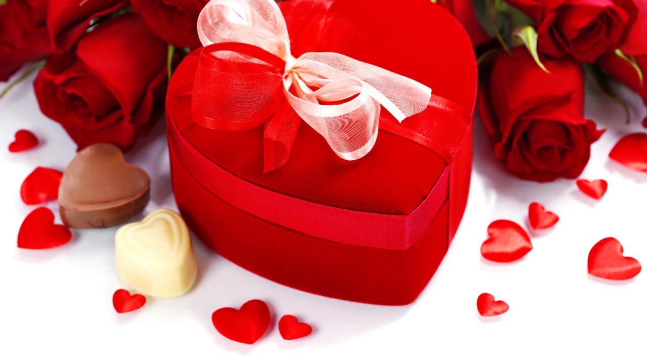 Красная коробка в форме сердца на столе с розами и конфетами для любимой