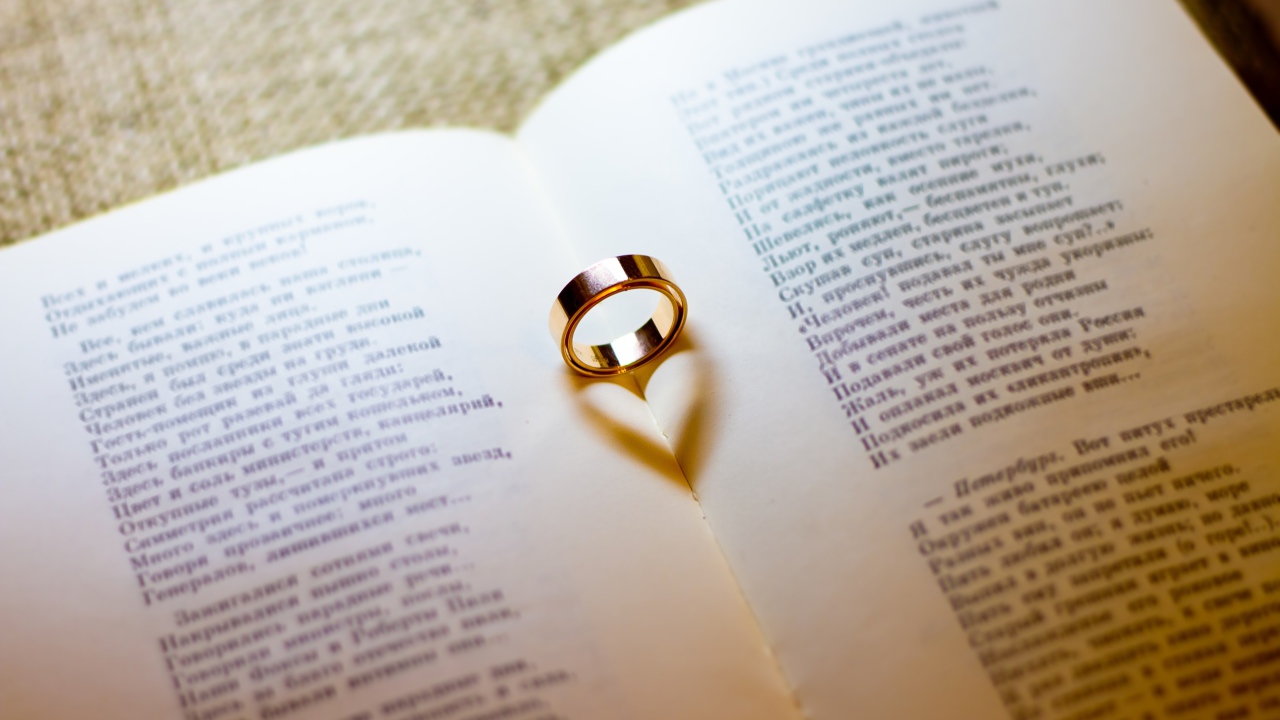 Золотое обручальное кольцо лежит на открытой книге