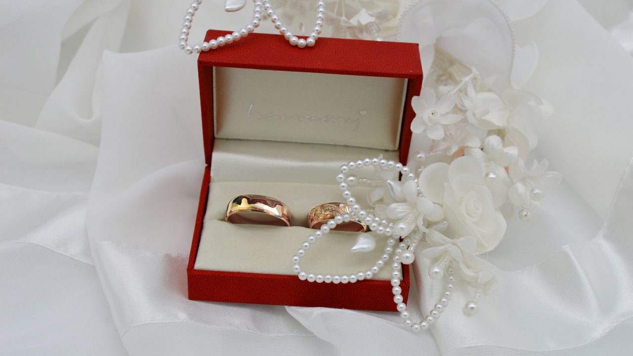 Золотые обручальные кольца в красной коробочке с украшениями