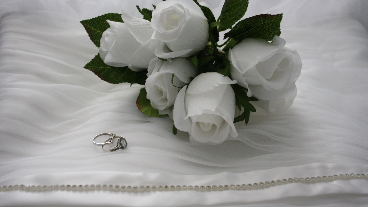 Белые бутоньерки с кольцами на белом покрывале 