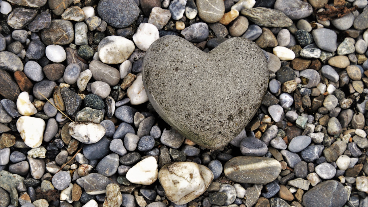 Большой камень в форме сердца лежит на морской гальке