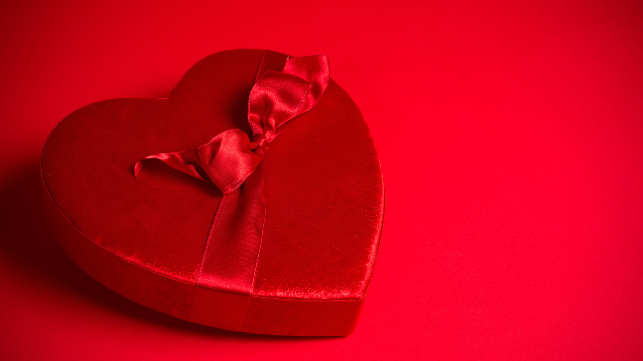 Большое красное сердце с бантом на красном фоне