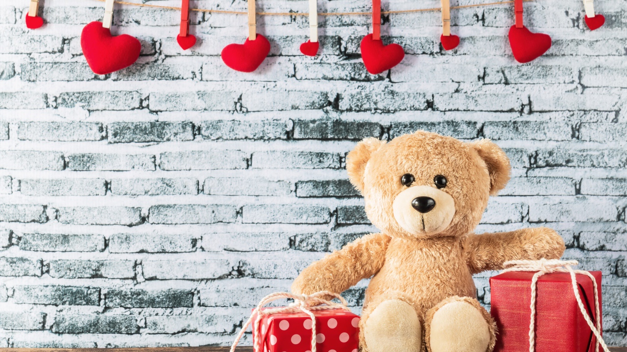 Медвежонок Тедди с подарками на фоне стены с сердечками