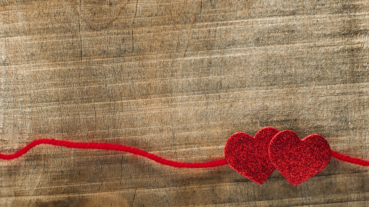 Два красных сердца со шнурком на деревянном фоне
