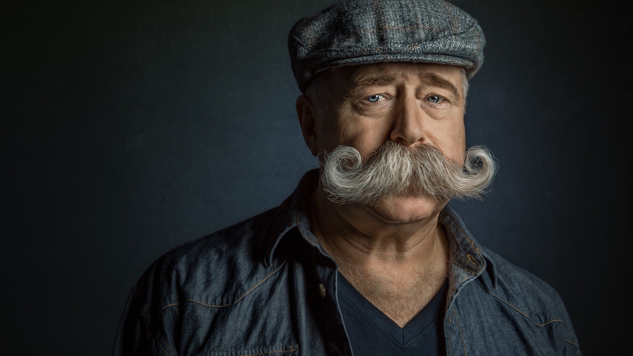 Мужчина в кепке с большими усами на лице 