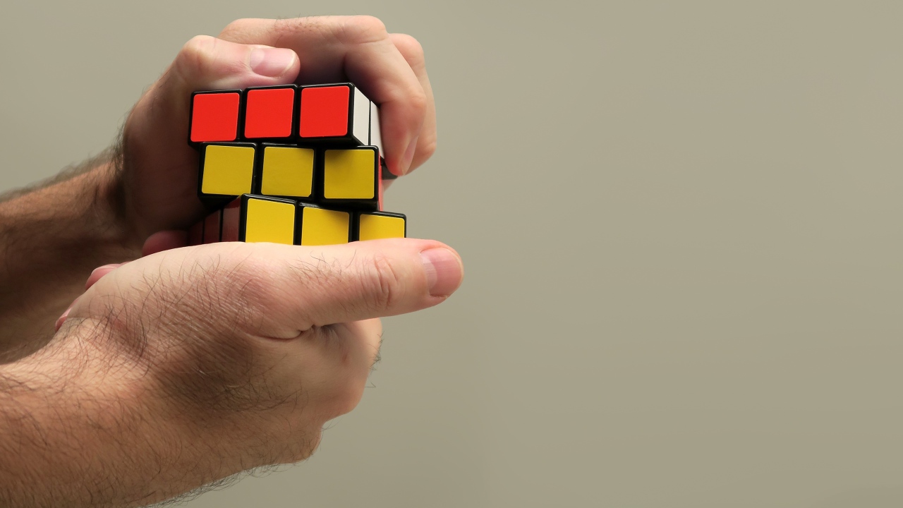 Rubik's cube in the hands of a man on a gray background